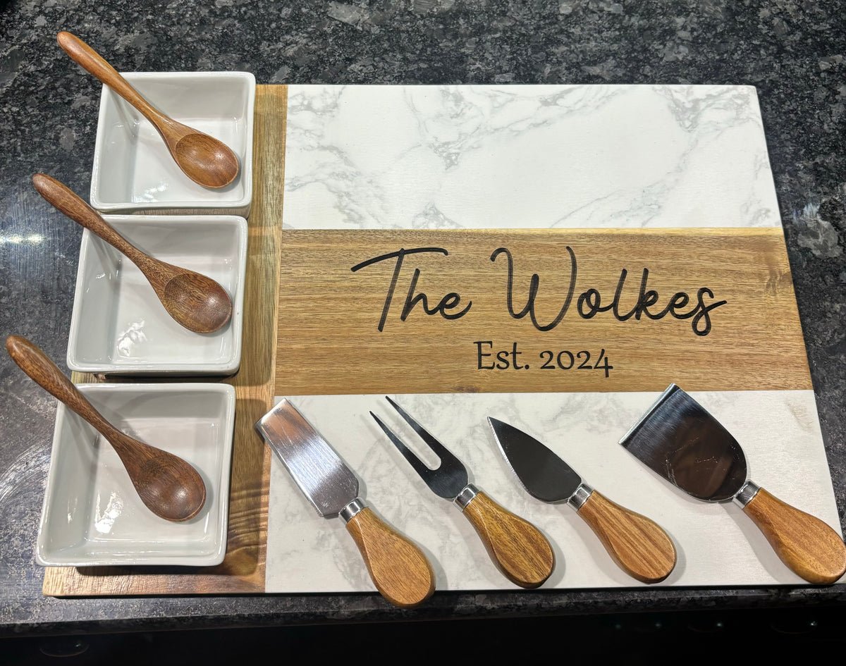 Charcuterie board with gold wood frame, three white bowls, and wooden-handled serving tools