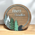 Round wooden name sign with forest trees, bear silhouette, and Rhett Walther