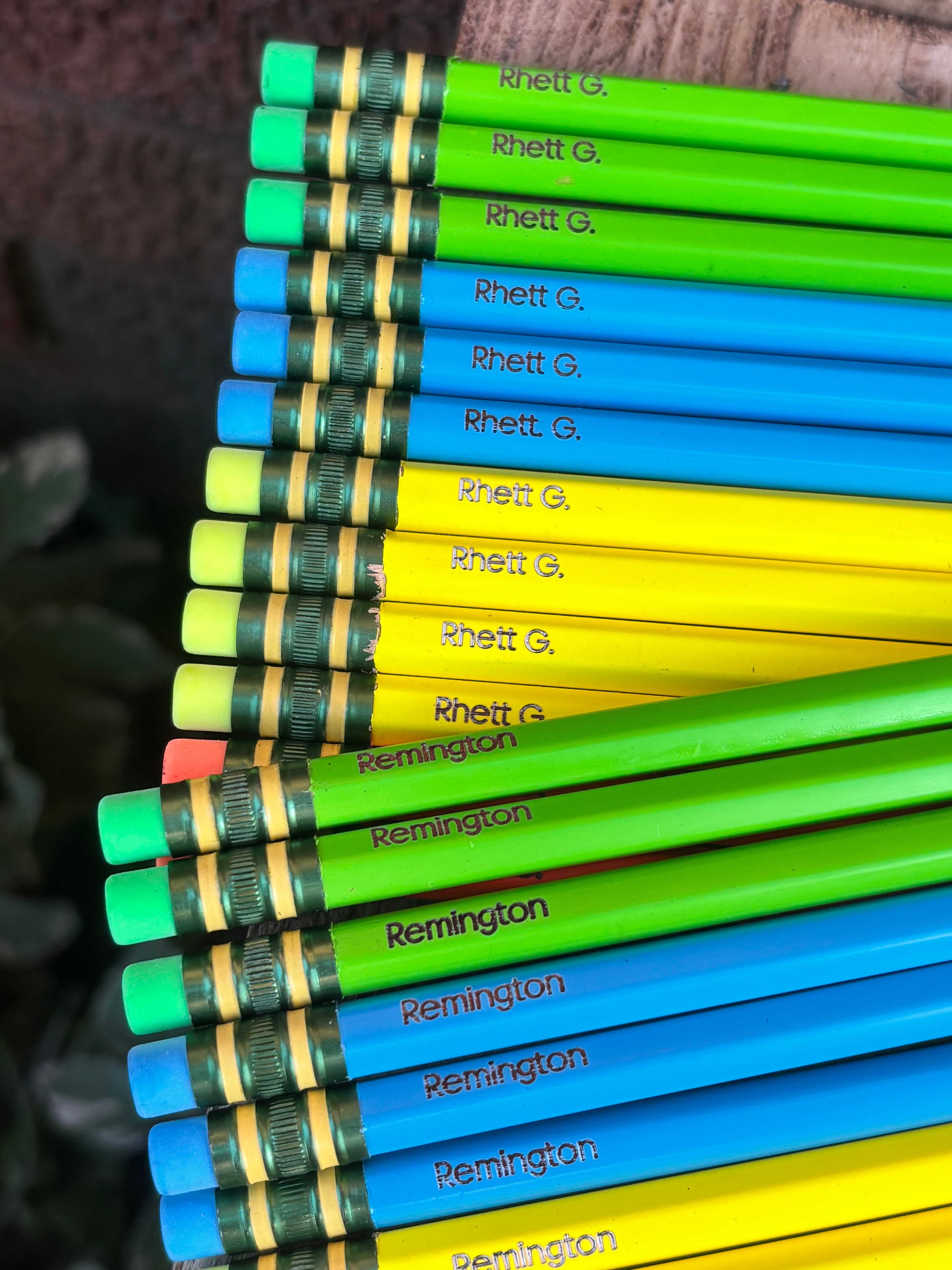 Neon colored pencils with printed names on barrels: green, blue, yellow, and teal