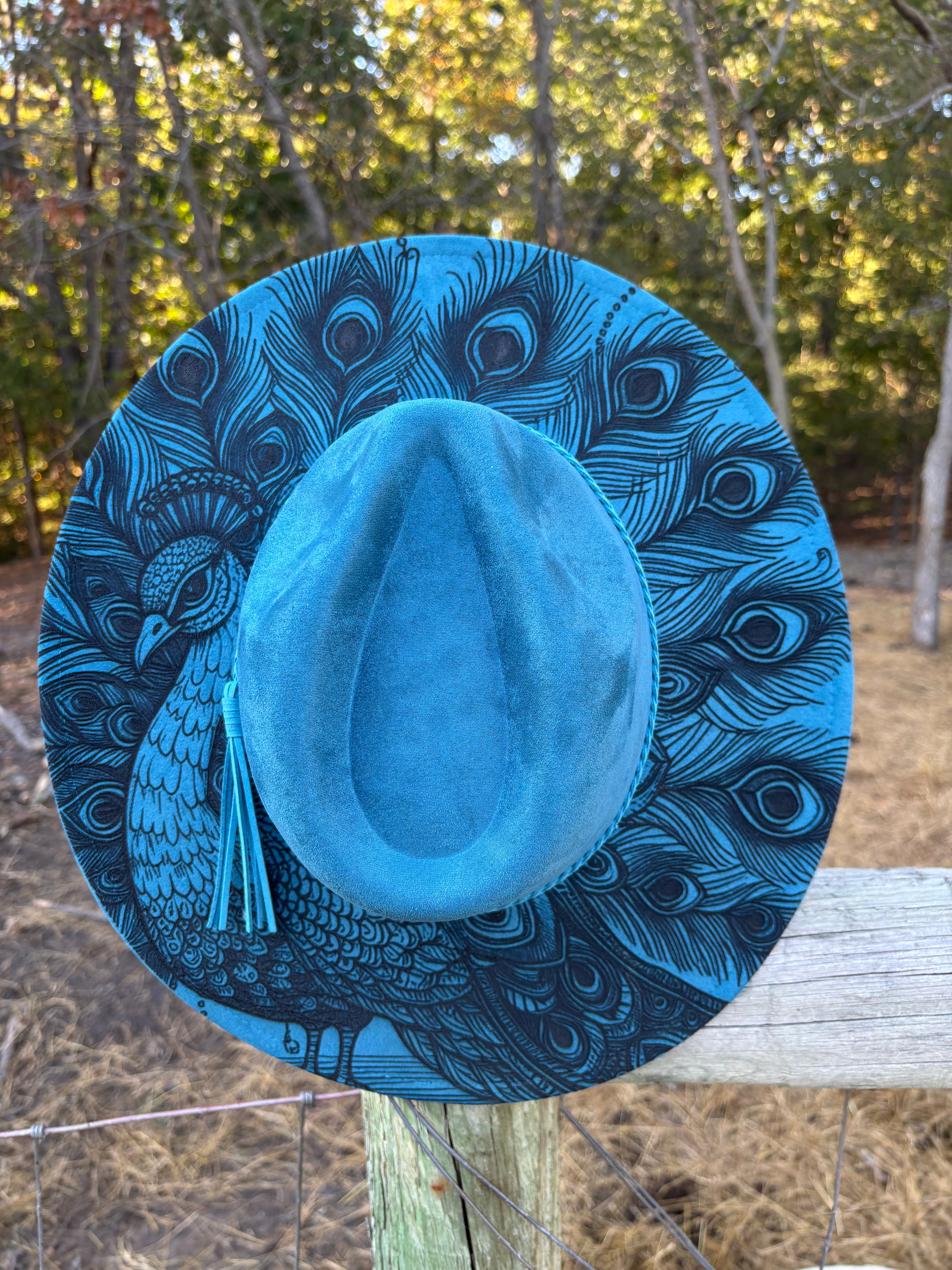 Blue suede hat with engraved peacock-feather pattern and tassel trim