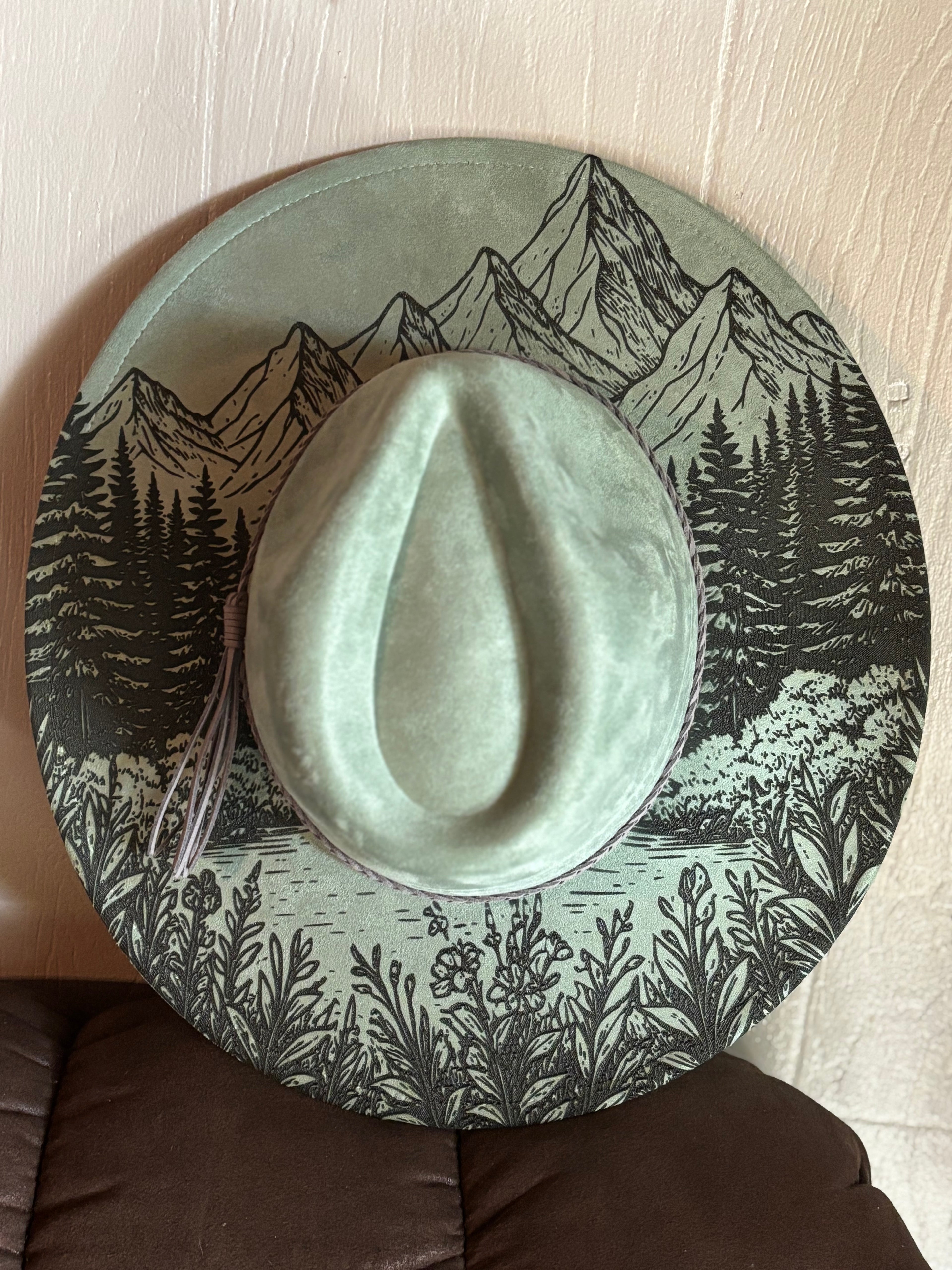 Sage suede hat with engraved mountains, pine trees, and dark forest pattern