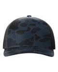Dark blue camouflage trucker cap with dark mesh side panels and curved brim