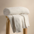 Plush weighted blanket, light cream with folded throw and soft textured surface